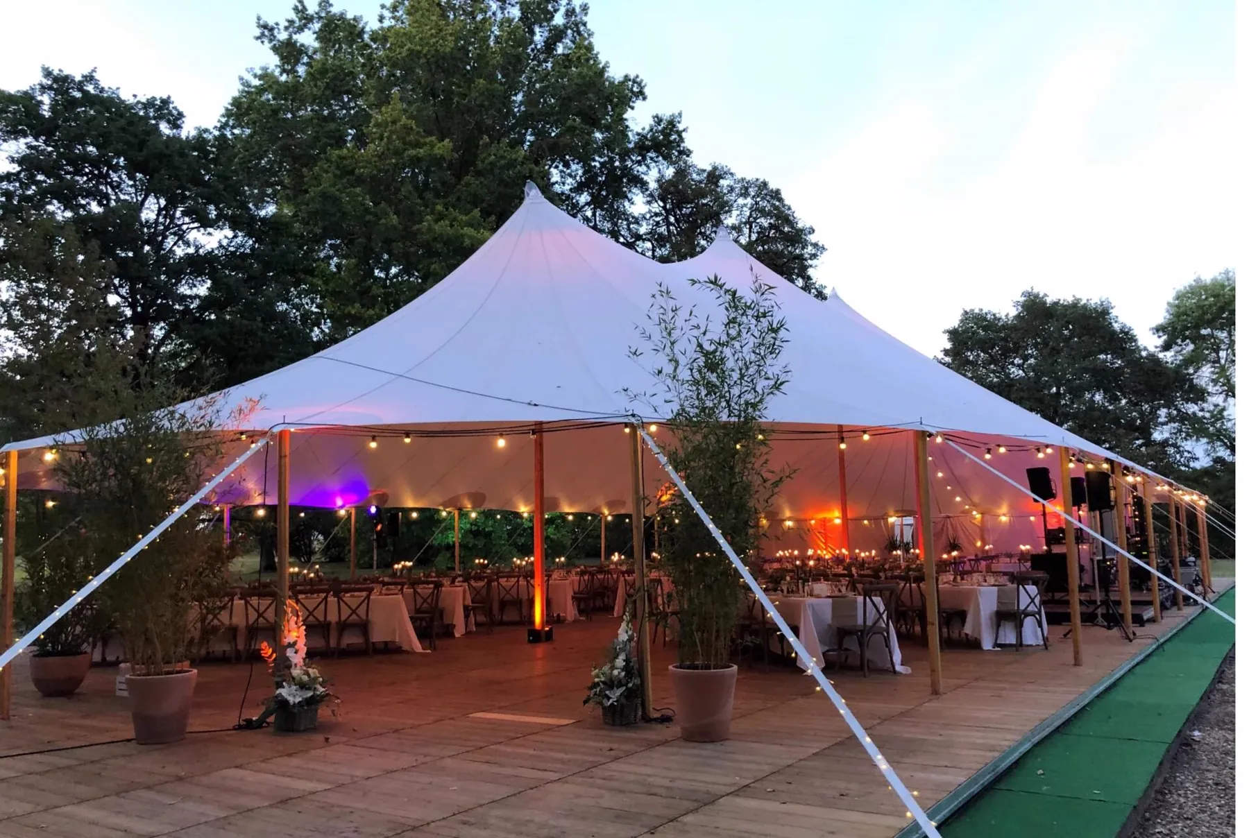 Grande tente de r&eacute;ception &agrave; la tomb&eacute;e du jour, guirlandes lumineuses et tables dress&eacute;es sous la toile