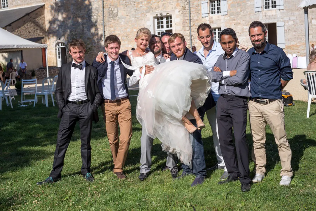 La mari&eacute;e port&eacute;e en riant par les gar&ccedil;ons d&rsquo;honneur, devant les b&acirc;timents de l&rsquo;abbaye