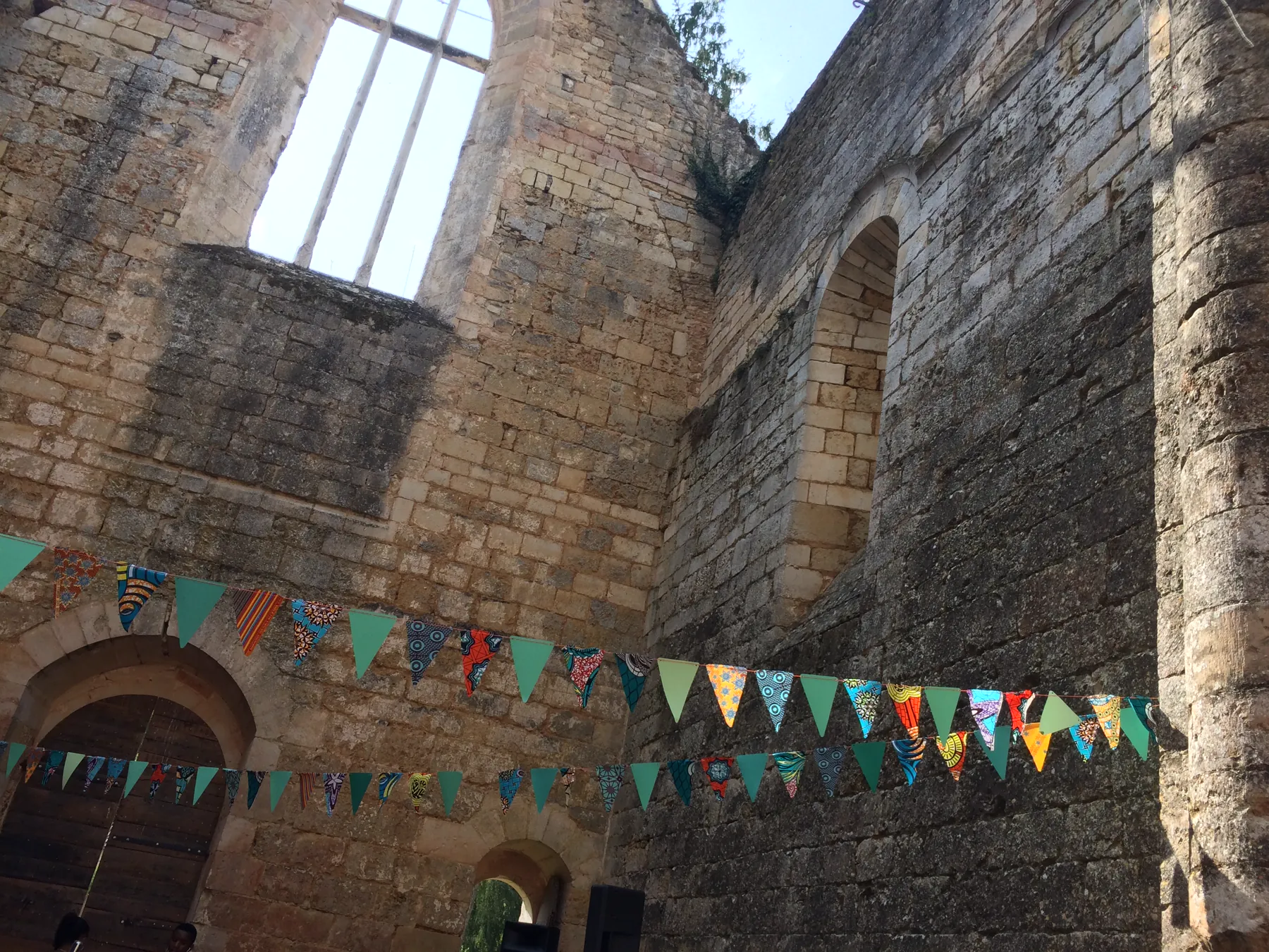 Les murs de l’ancienne chapelle en ruine, ouverte sur le ciel, traversés de deux guirlandes de fanions