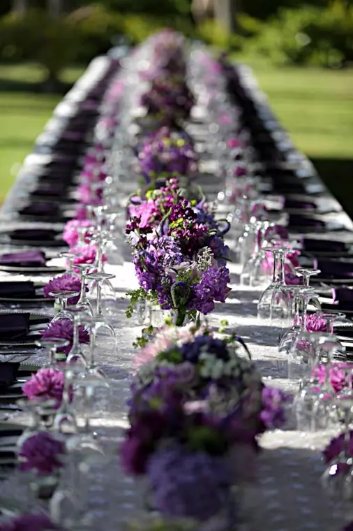 Grande table mariage. Serviettes violettes et nappe blanche - centre de table de bouquets violets