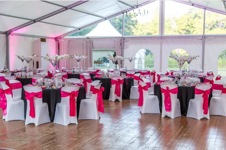 Le tivoli dressé : housses blanches à nœuds fuchsia, nappes noires, vases hauts