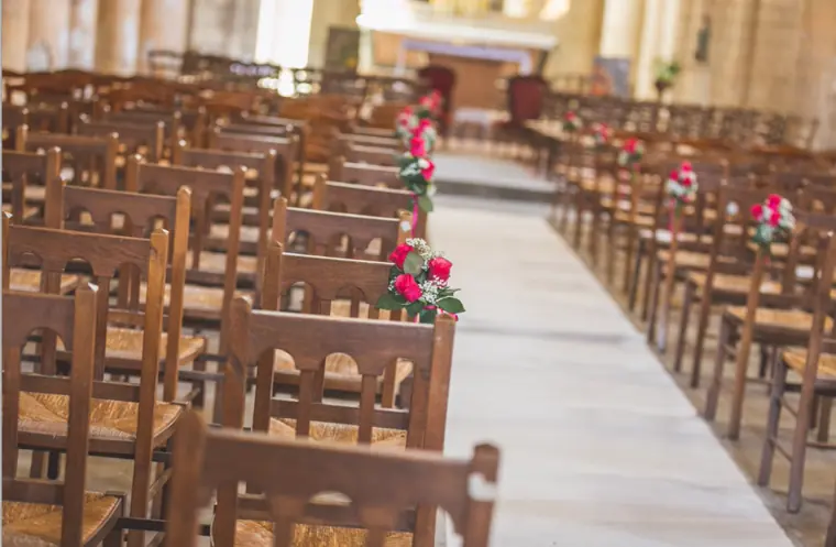 L’allée de l’église, des bouquets de roses fuchsia aux bouts de bancs