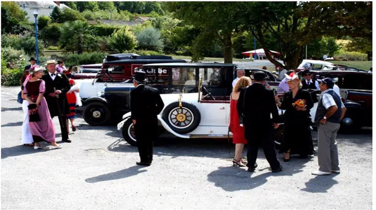 Les invités en costume, rassemblés autour des voitures avant le départ du rallye