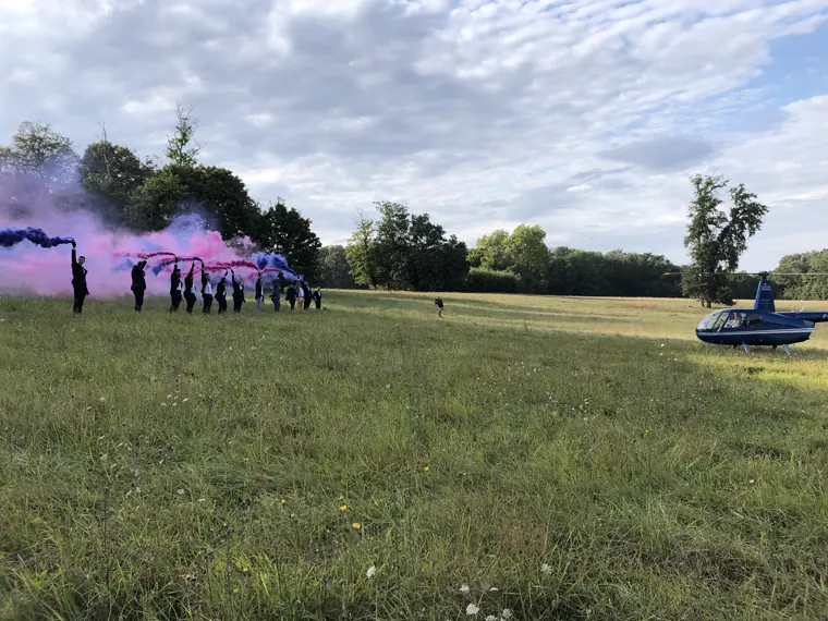 L’hélicoptère posé dans le champ, au milieu des fumigènes roses