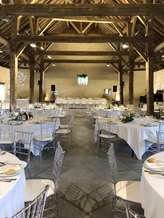 Les tables rondes dressées sous la charpente de la grange