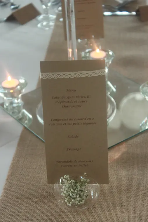 Le menu en kraft posé sur un miroir, entre les photophores