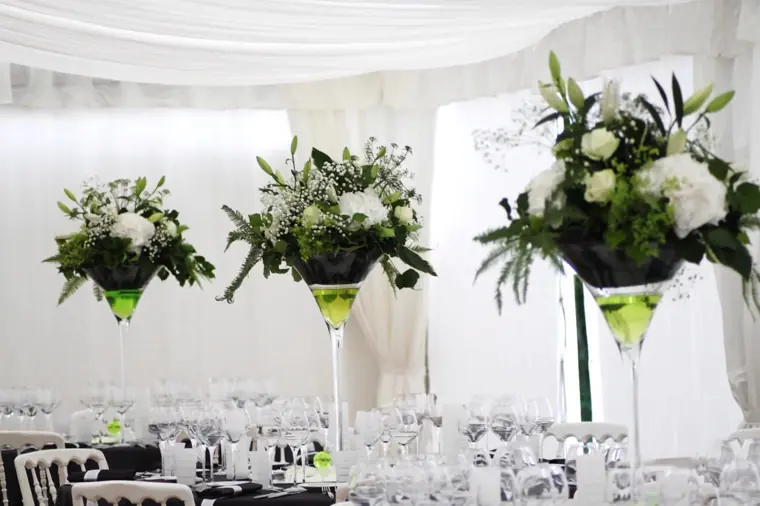 centres de table en vases martini garnis de roses blanches et de feuillage, sous le tivoli