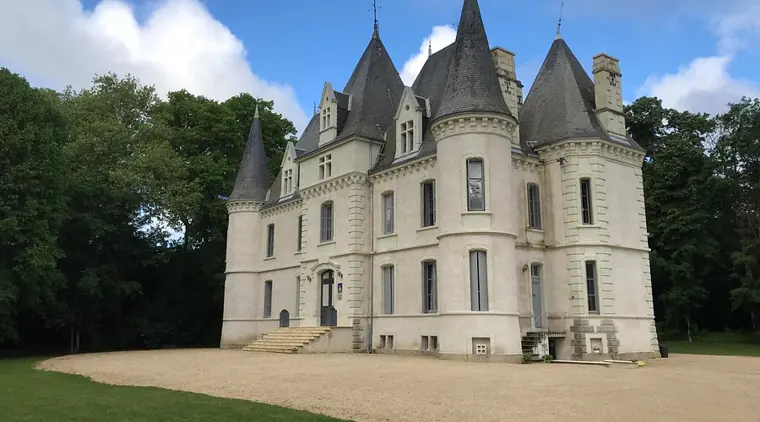 Le château de Baillant, sa façade claire et ses tourelles d’ardoise, devant la cour de gravier