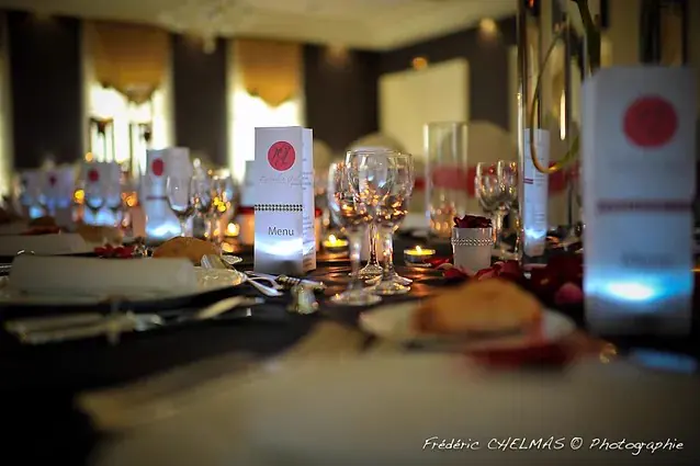 La table du dîner : nappe sombre, menus monogrammés, pétales et bougies