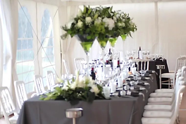 longue table sous le tivoli, vases martini fleuris et chaises en bois blanches