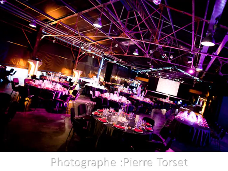 La halle de l’ancienne carrière, dressée en tables rondes sous la charpente métallique et les lumières violettes