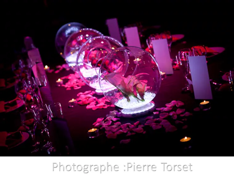 L’alignement des boules de verre et des pétales de rose sur la longueur de la table
