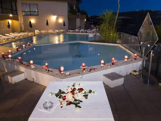 la piscine entouree de bougies a la tombee du jour, table blanche et fleurs