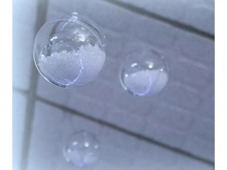 boules transparentes remplies de fausse neige, suspendues devant un mur clair