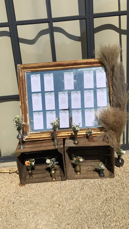 Le plan de table sur miroir, encadré de pampas et posé sur des caisses de bois