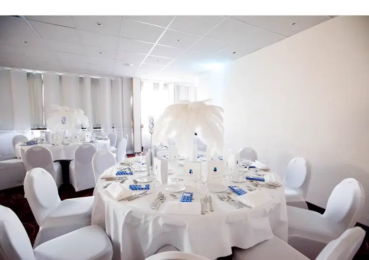 La salle entièrement blanche, housses de chaises et plumes sur chaque table