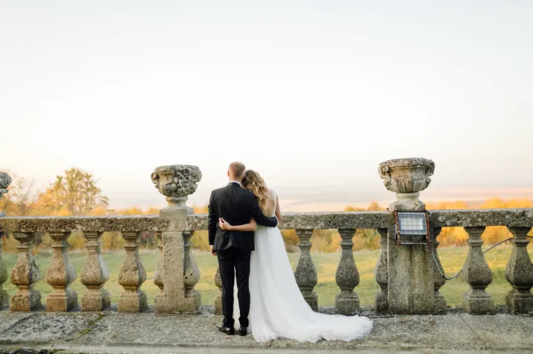 Un couple de dos, accoudé à une balustrade de pierre, regardant la vallée au crépuscule