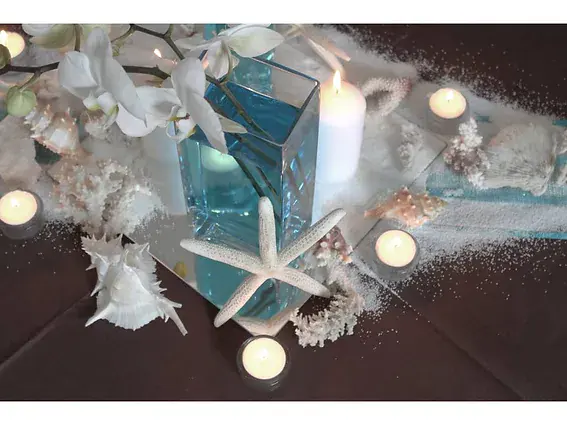 bougie blanche entouree d etoiles de mer, de sable et de vases turquoise