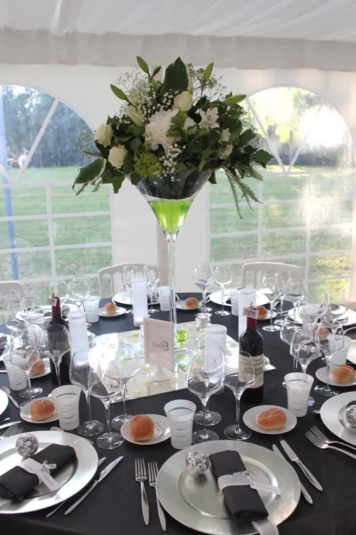 couvert dresse en gris et blanc, serviette pliee et centre de table en vase martini