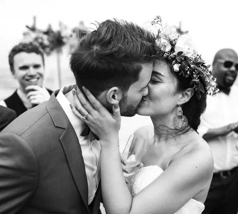 Une mariée coiffée d’une couronne de roses et d’eucalyptus, embrassant son mari