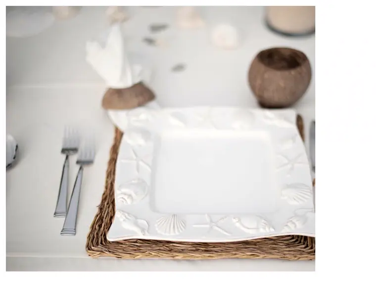 detail d un couvert : assiette carree blanche, serviette pliee et set en rotin