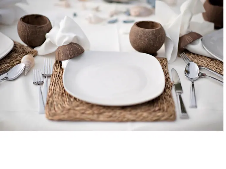 couvert pose sur un set en rotin tresse, assiette carree blanche et noix de coco