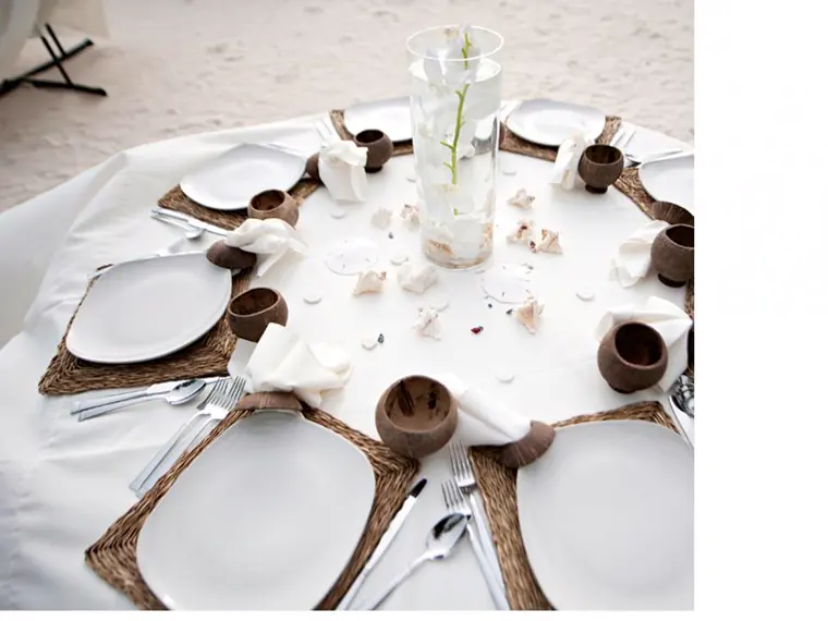 table ronde dressee sur le sable, verrines servies dans des noix de coco et coquillages