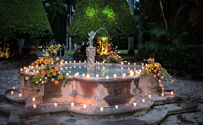 la fontaine du domaine, entouree de bougies et de fleurs a la tombee de la nuit