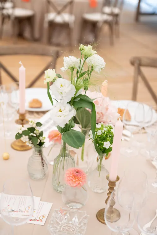 Détail d’un centre de table : lisianthus, bougies et bouteille de vin