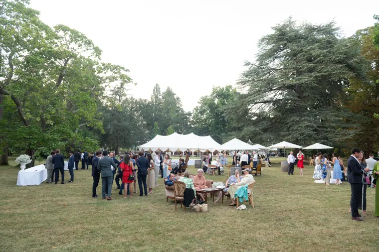 Vue large du cocktail dans le parc, devant la façade du château