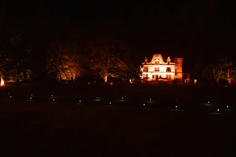 Le château illuminé dans la nuit, vu depuis le parc