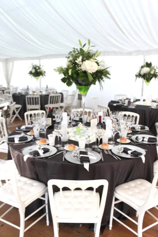 table ronde nappee de gris fonce, assiettes blanches et chaises medaillon