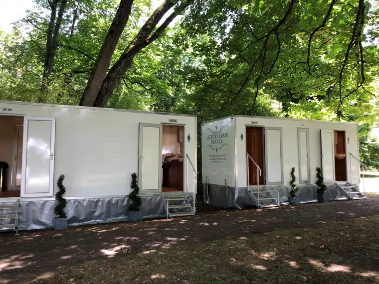 Les deux remorques sanitaires installées sous les arbres du parc