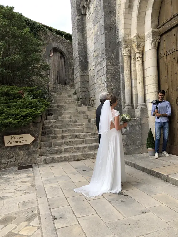 La mariée devant le portail roman de la collégiale, sous l’objectif du photographe