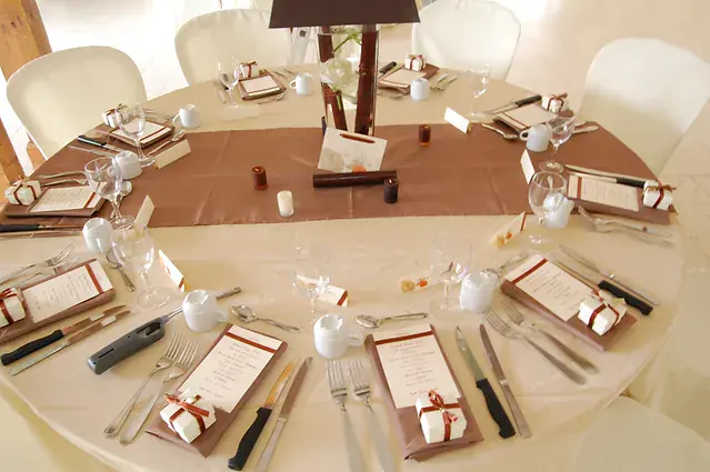 table ronde en chocolat et ivoire, menus poses sur chaque assiette