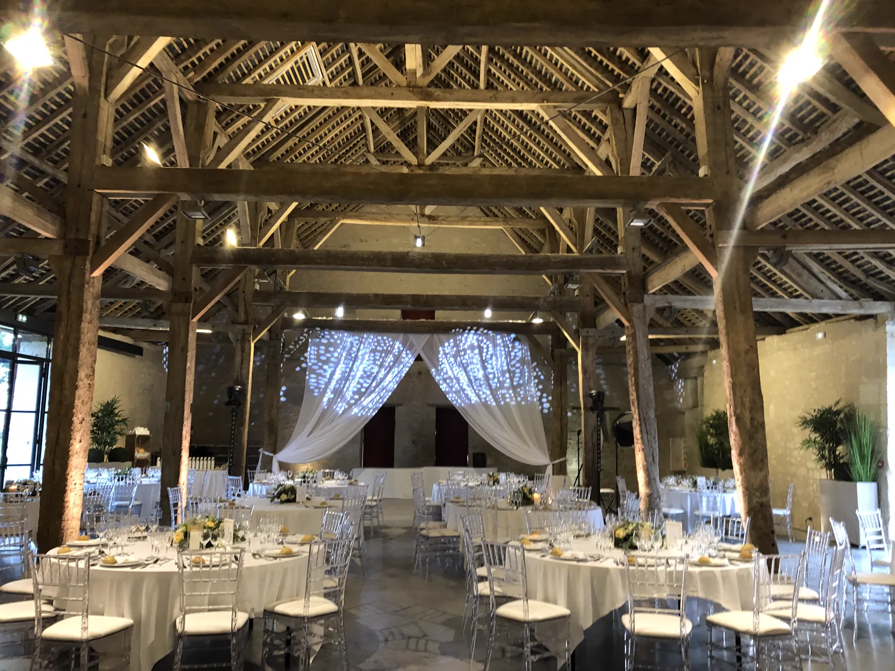 Une grange ancienne transform&eacute;e en salle de mariage, drap&eacute;s blancs et guirlandes lumineuses