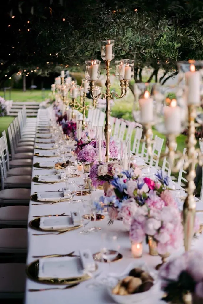 Table dress&eacute;e en ext&eacute;rieur, couverts dor&eacute;s et grands chandeliers
