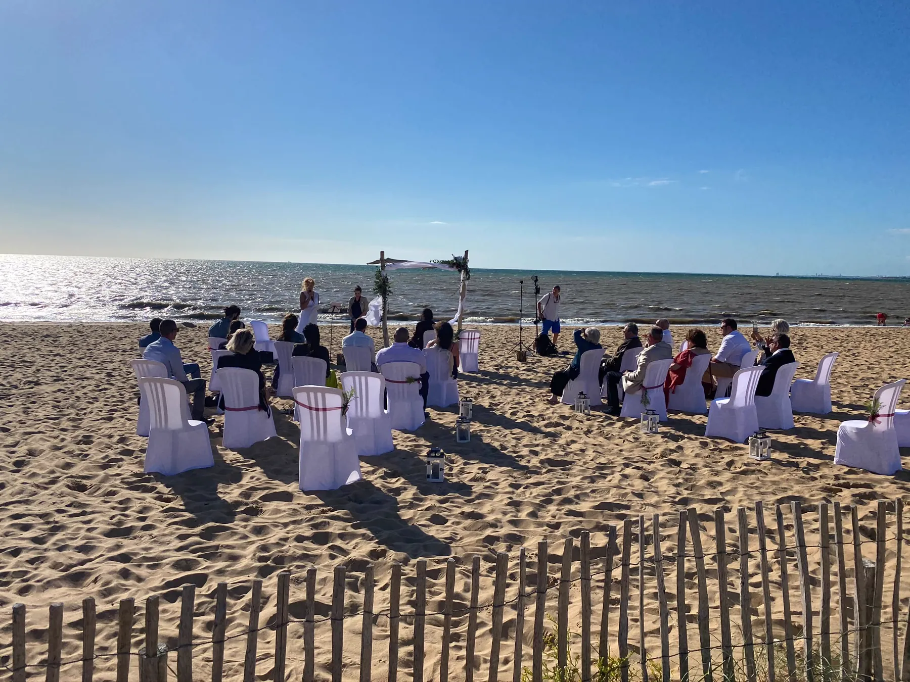 Une cérémonie sur le sable : une trentaine de chaises houssées, une arche en bois flotté et le tissu couché par le vent