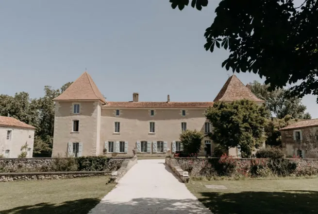 Le château de la Mothe vu de face depuis l’allée, sa pierre claire et ses deux tours à toits de tuiles