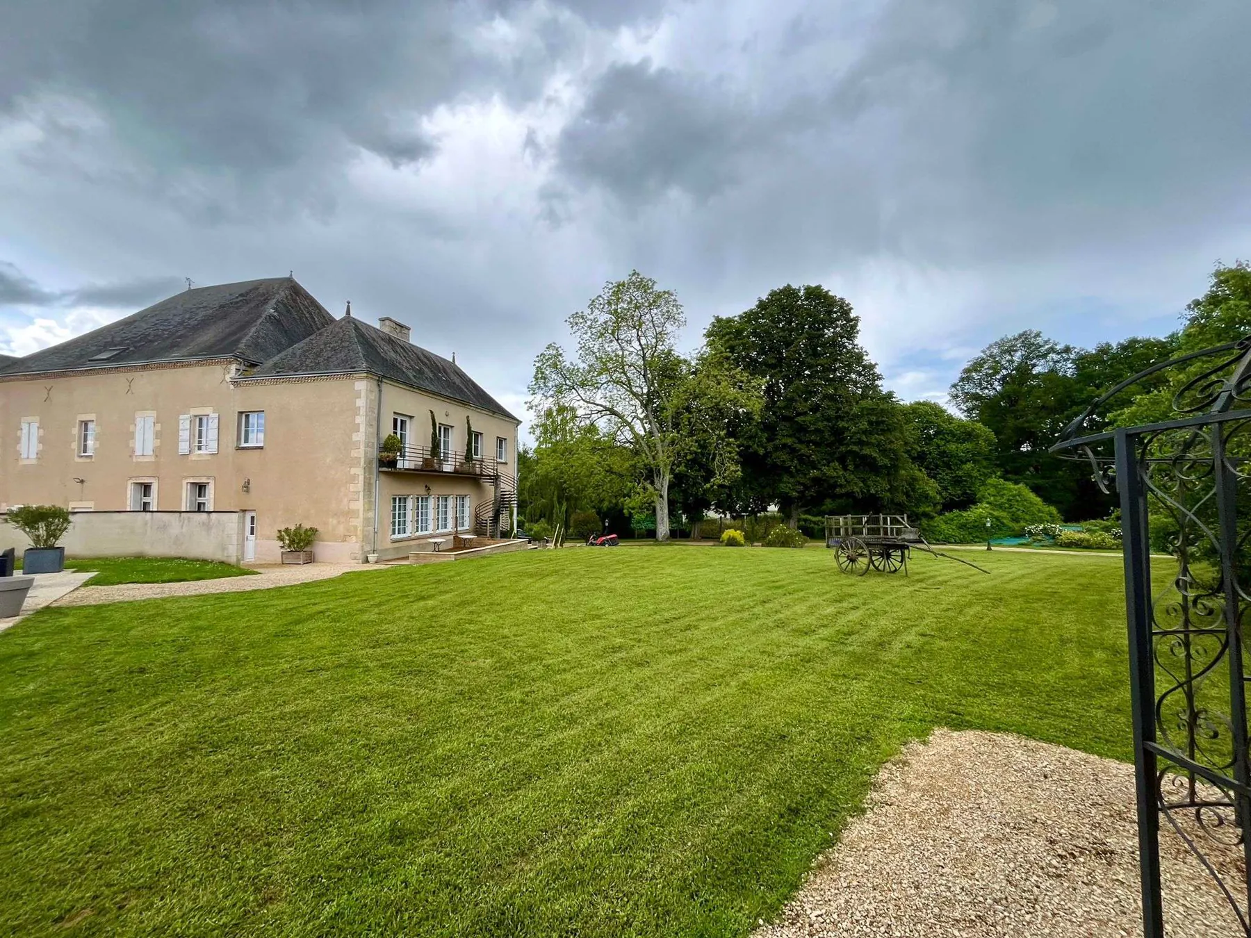 Le château de Montbeil vu du parc, sa grande pelouse et la gloriette en fer forgé