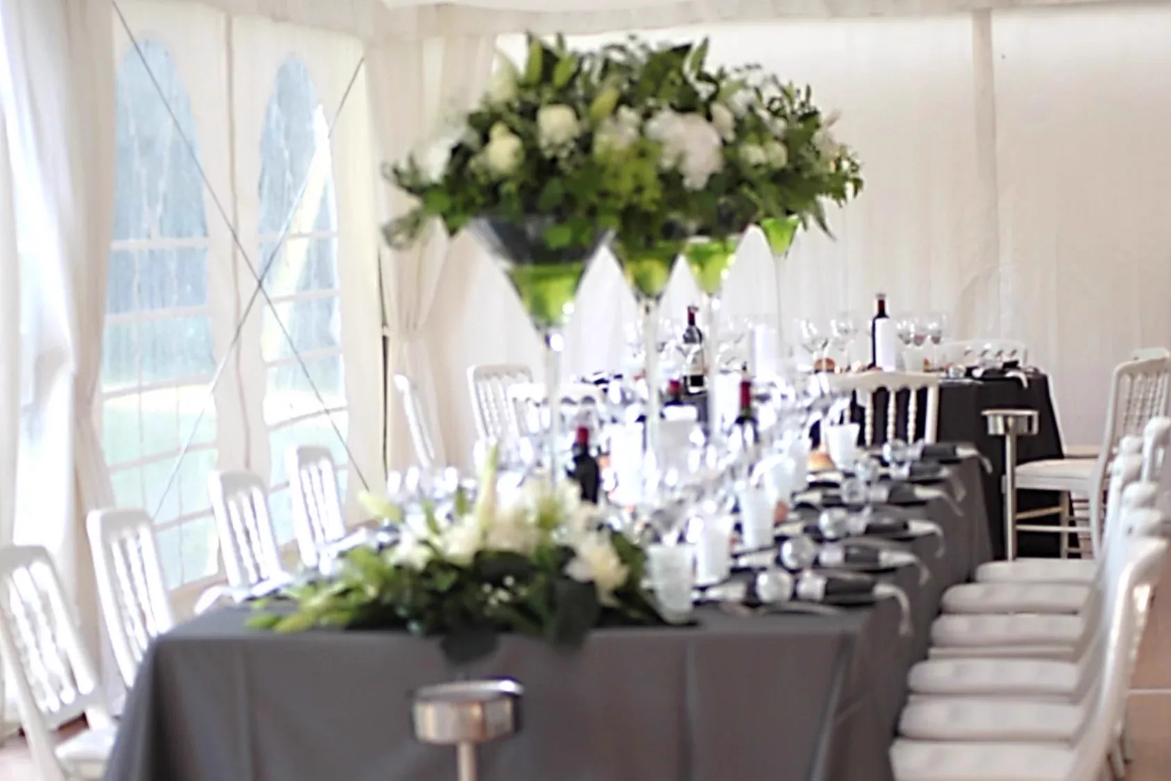 Sous le tivoli : vases Martini fleuris et chaises en bois blanches