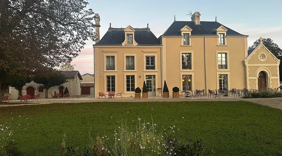 La façade de la demeure au crépuscule, la chapelle accolée sur la droite, et la pelouse devant