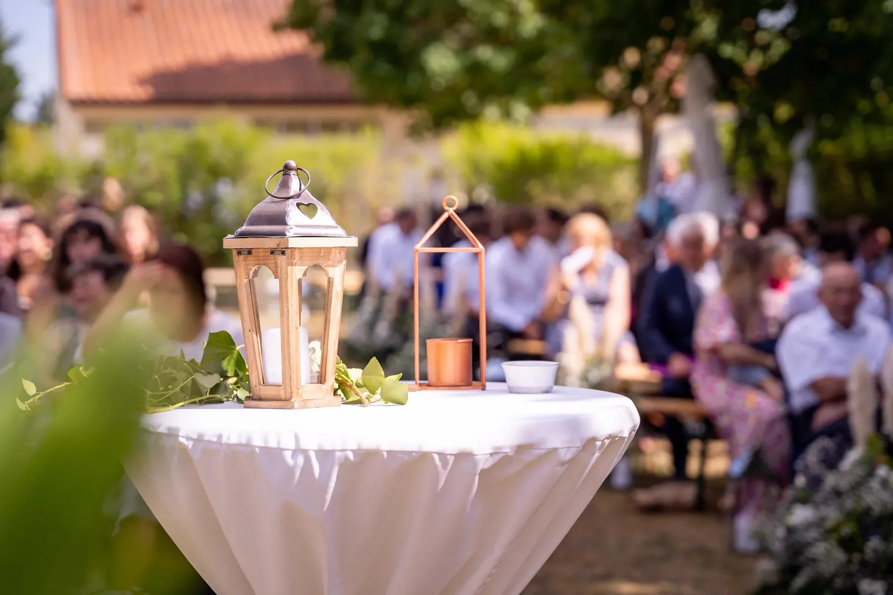 Une bougie allumée dans sa lanterne, posée sur une table blanche pendant la cérémonie
