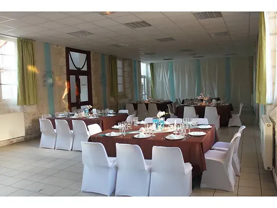 La m&ecirc;me salle habill&eacute;e de voilages turquoise et blancs, tables en chocolat et housses blanches