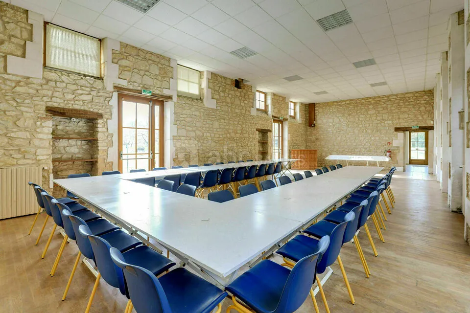 La grande salle du Coqvert, ses murs en pierres apparentes et son parquet de chêne, dressée en tables