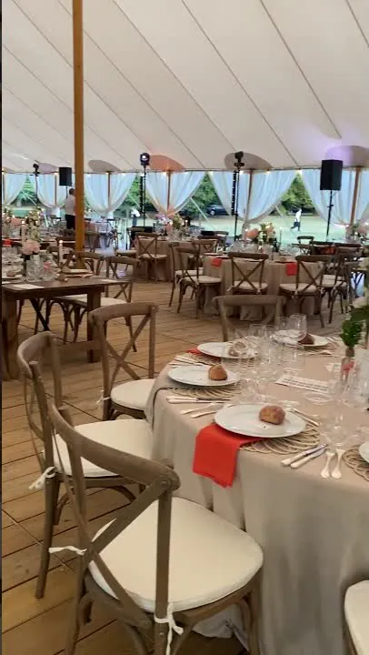 La tente de r&eacute;ception dress&eacute;e, tables rondes et serviettes corail, avant l&rsquo;arriv&eacute;e des invit&eacute;s