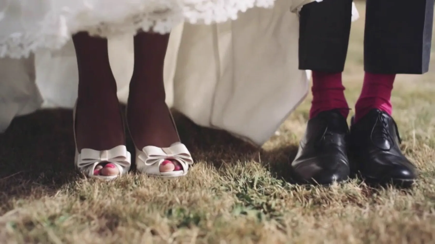 Les chaussures des mari&eacute;s pos&eacute;es dans l&rsquo;herbe : escarpins ivoire et chaussettes fuchsia