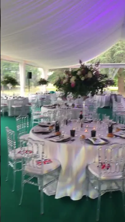 Sous le tivoli : plafond drap&eacute;, &eacute;clairage violet, hautes compositions florales et chaises transparentes