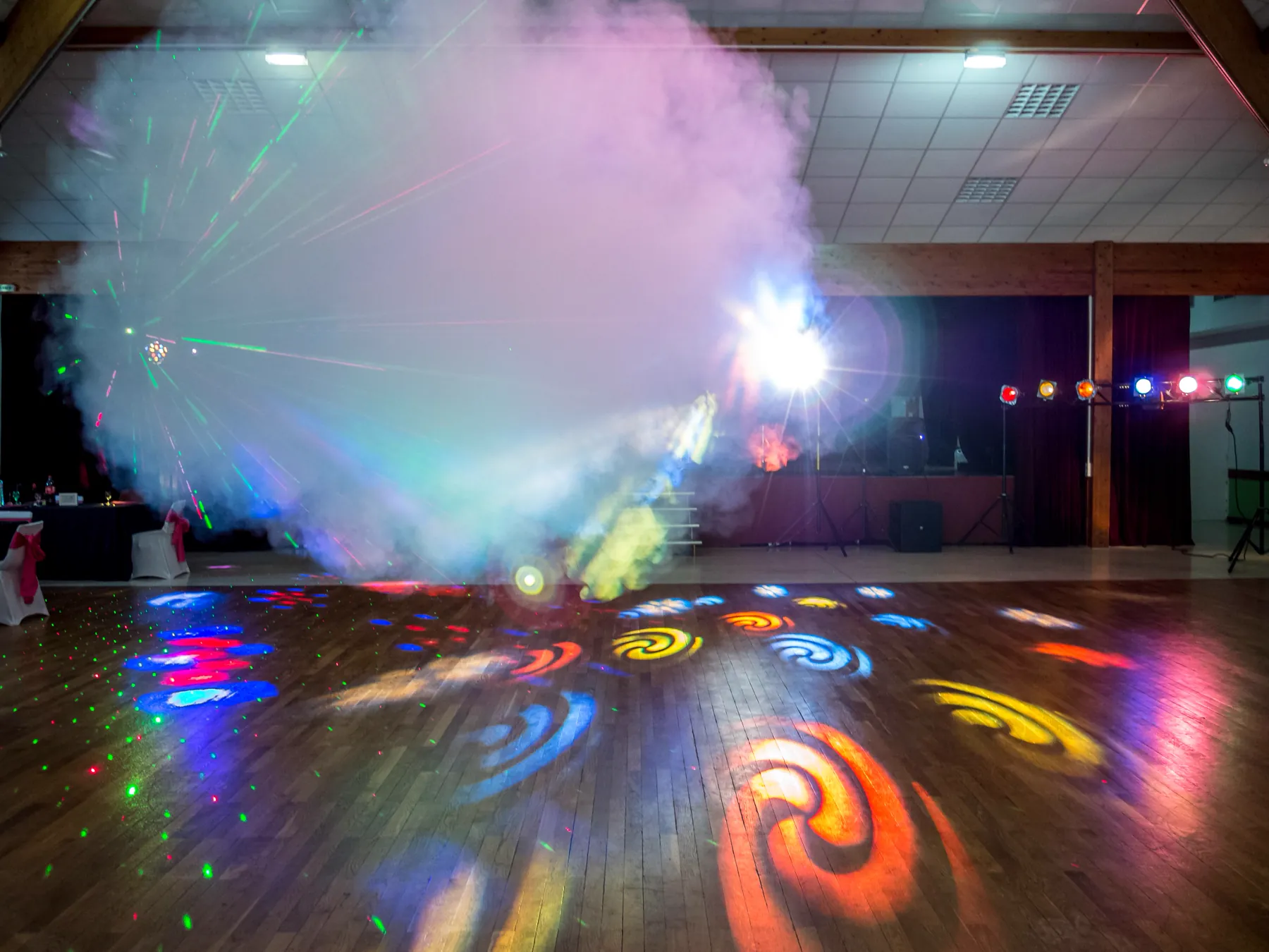 La piste de danse éclairée de lasers et de gobos colorés, la régie du DJ et ses projecteurs sur pieds au fond de la salle
